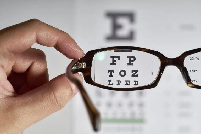 Eyeglasses held in front of an eye chart